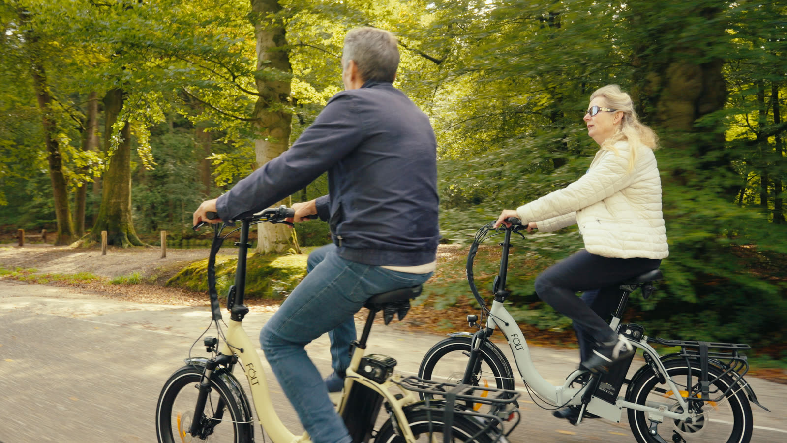 Stel fietst samen op FOLT elektrische vouwfietsen over een bosweg