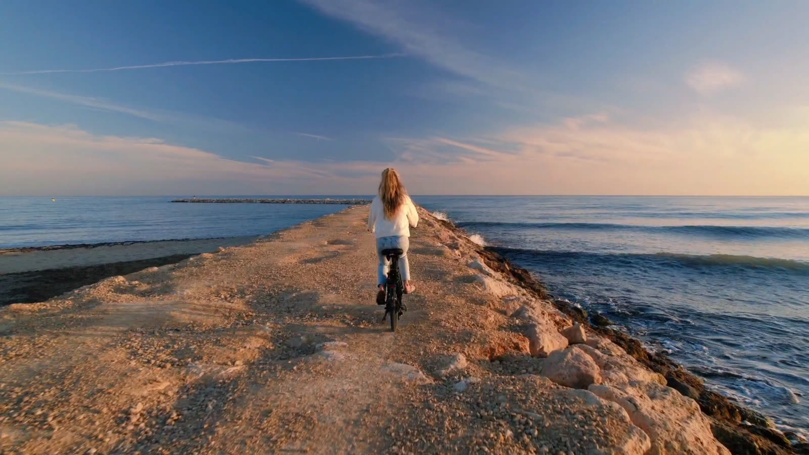 Fietser op een FOLT vouwfiets over een pier richting zee bij zonsopkomst
